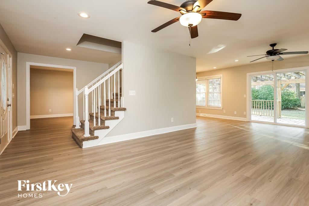A spacious room with a staircase and a ceiling fan.