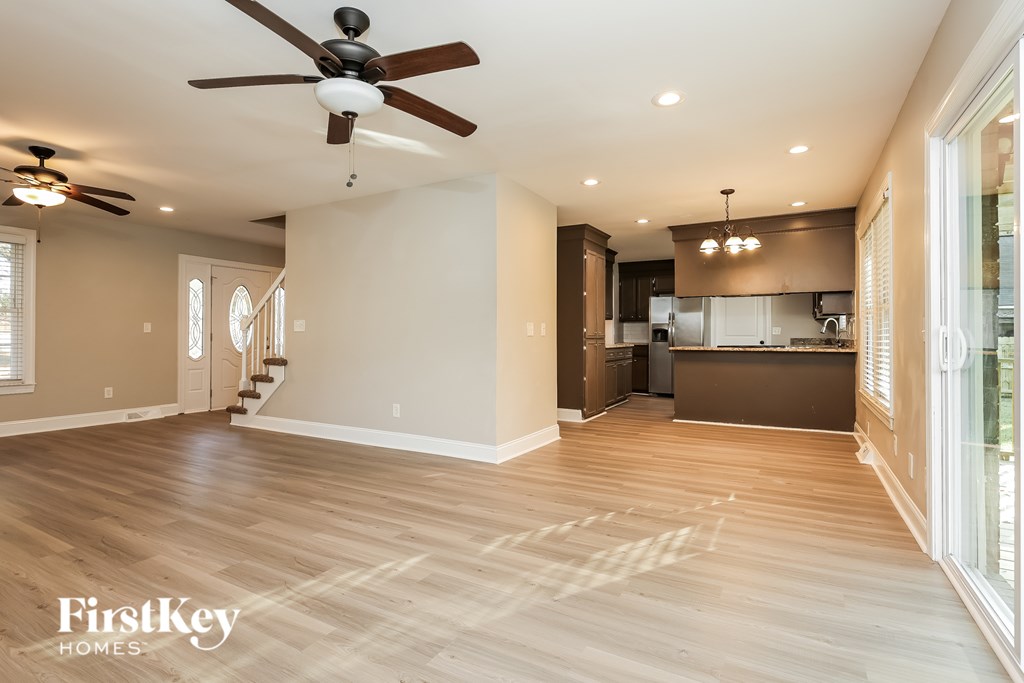 A spacious kitchen and living room with a wood floor and a ceiling fan.