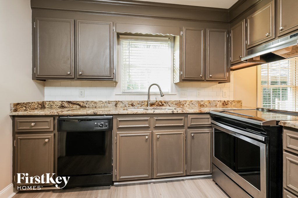 A kitchen with brown cabinets and a stone backsplash.