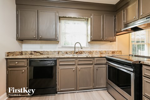A kitchen with brown cabinets and a stone backsplash.