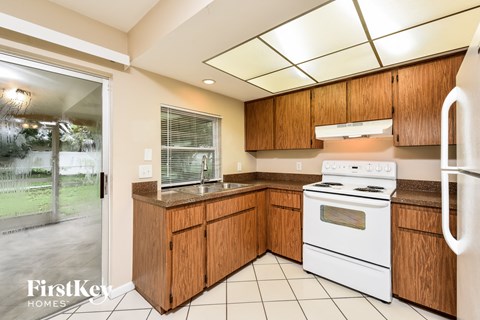 A kitchen with wooden cabinets and a white stove top oven.