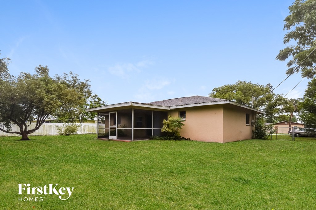 A house with a green lawn and trees in the background.