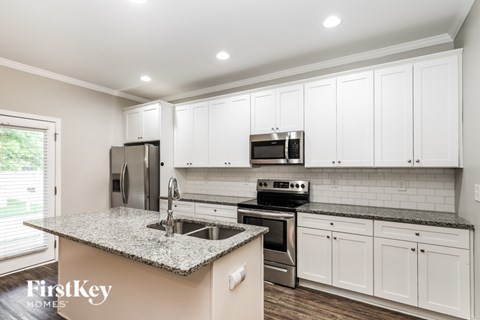 A kitchen with granite countertops and white cabinets.