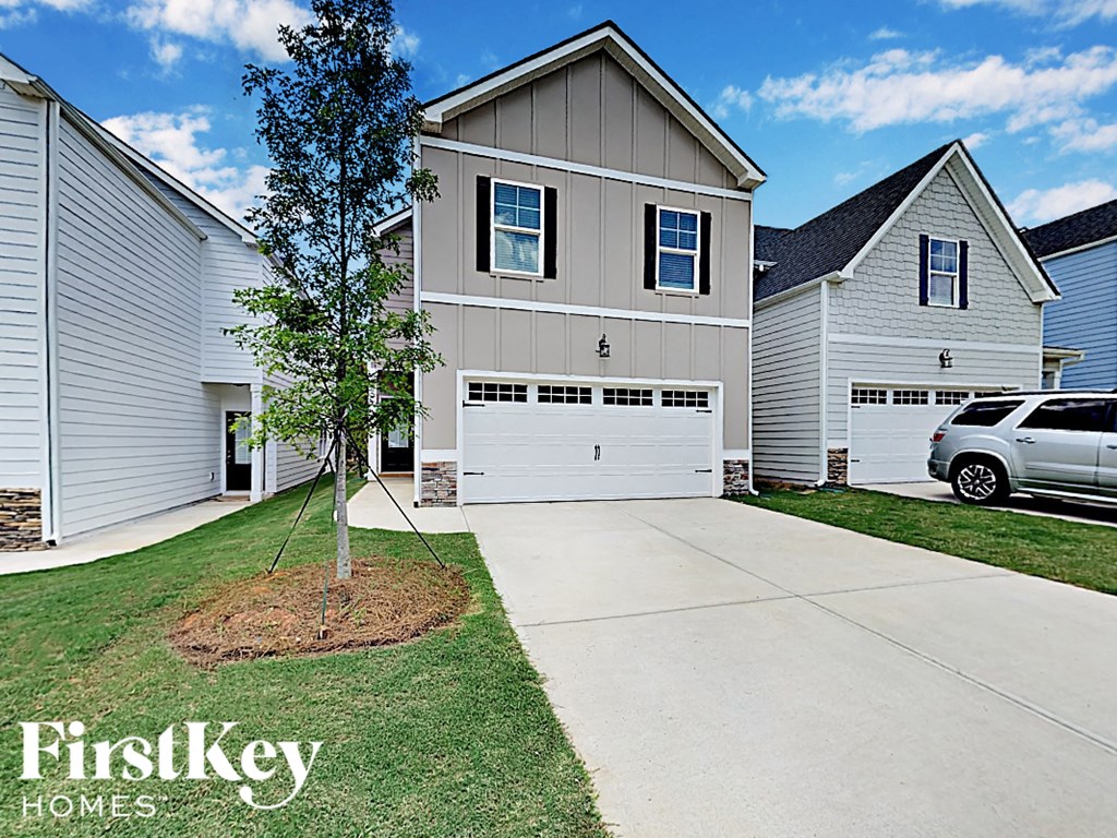 A tree in a mulched area in front of a house with a garage door.