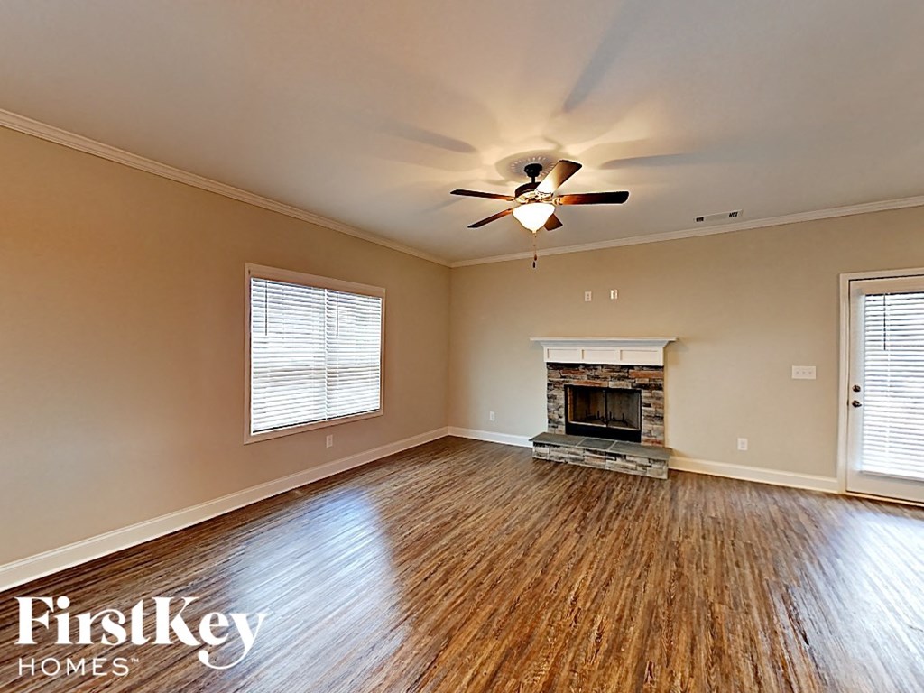 A spacious room with a fireplace and wooden floors.