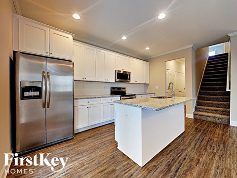 A kitchen with a refrigerator, microwave, and stove top oven.