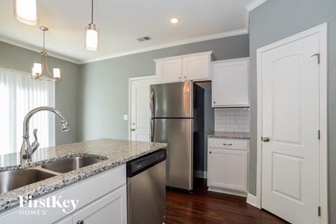 A kitchen with a stainless steel refrigerator and a granite countertop.