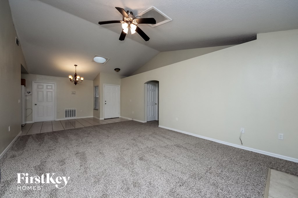 A spacious room with a ceiling fan and carpeted floor.