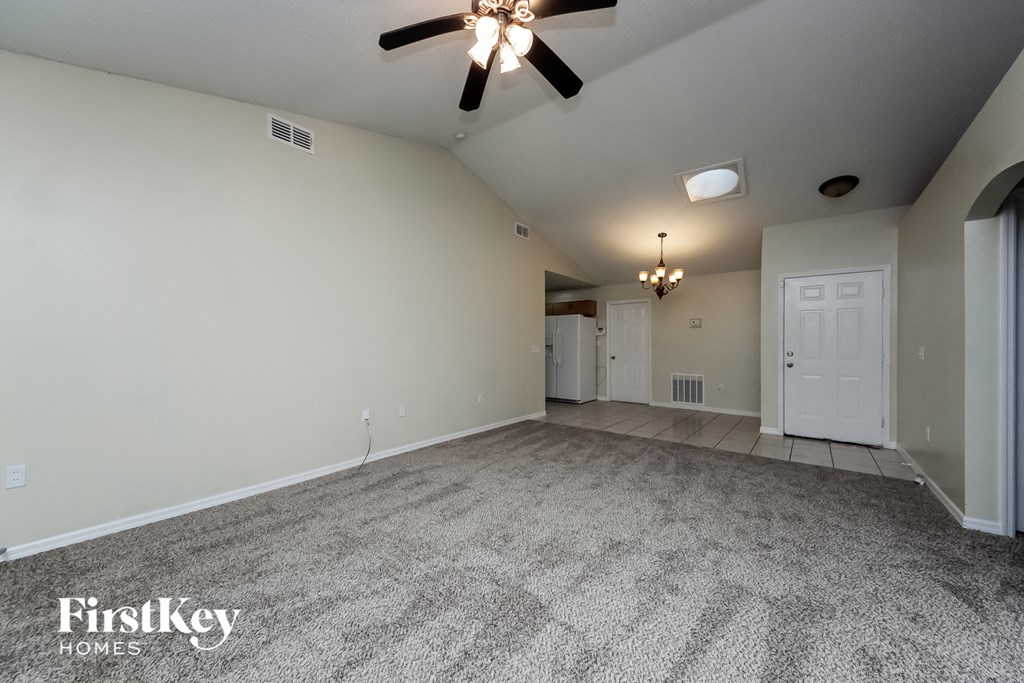 A spacious room with a ceiling fan and carpeted floor.