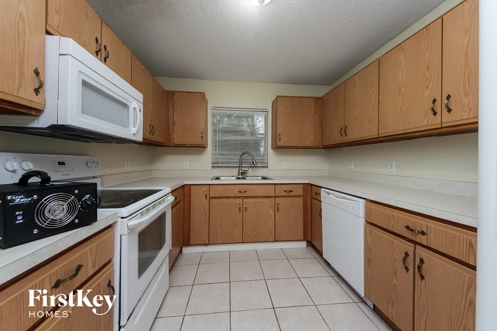 A kitchen with wooden cabinets and a white microwave.