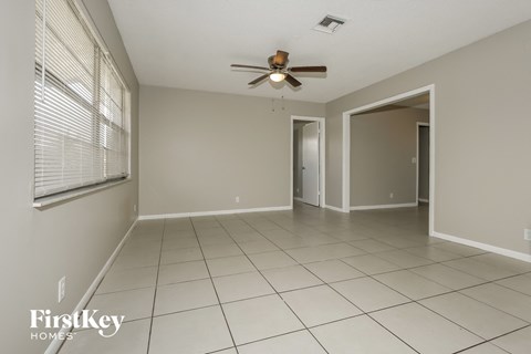 A spacious room with a ceiling fan and tiled flooring.
