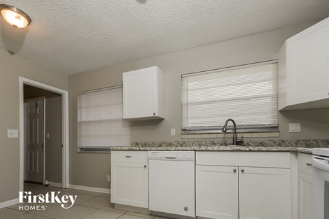 A kitchen with white cabinets and a granite countertop.