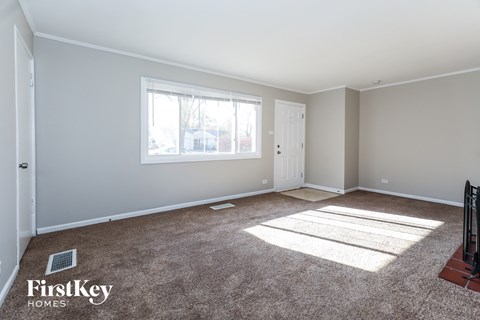 A room with a carpeted floor and a window letting in sunlight.