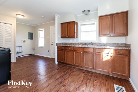 A kitchen with wooden cabinets and a black fridge.