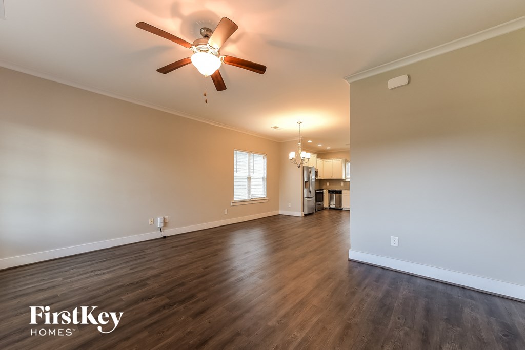 the living room of an empty house with a ceiling fan