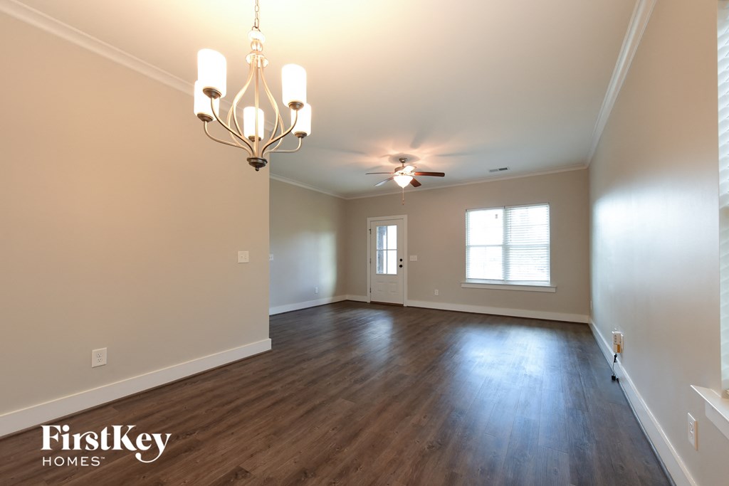 an empty living room with wood floors and a chandelier