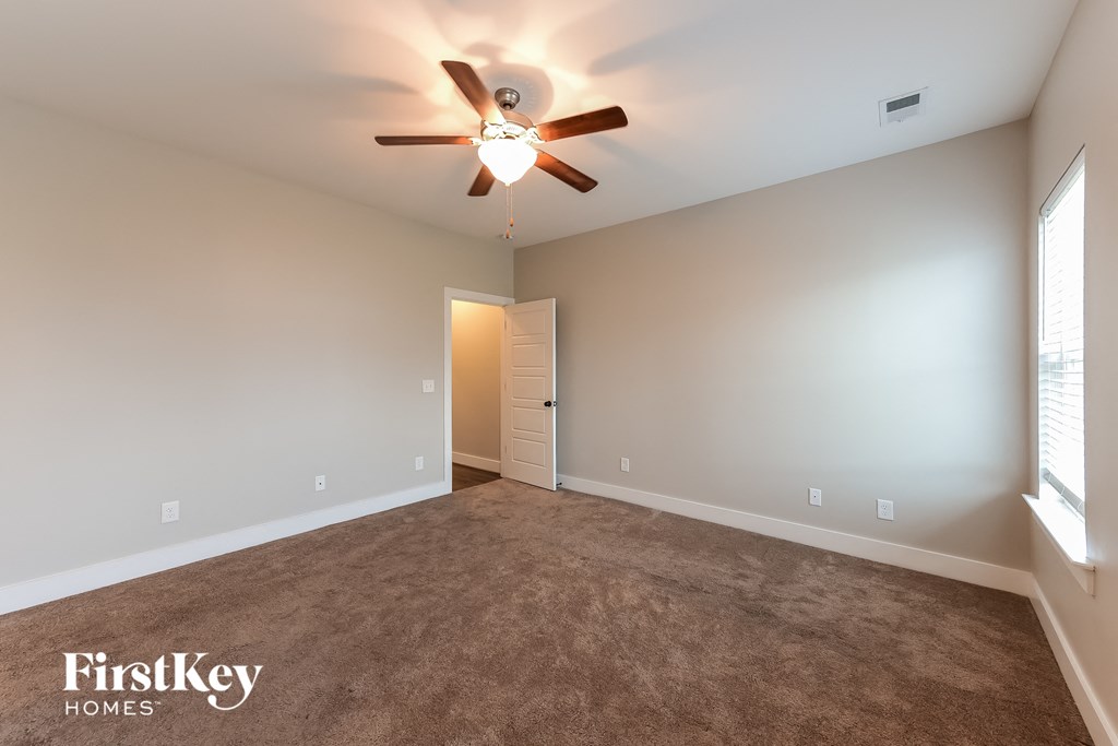 the master bedroom has a carpeted floor and a ceiling fan
