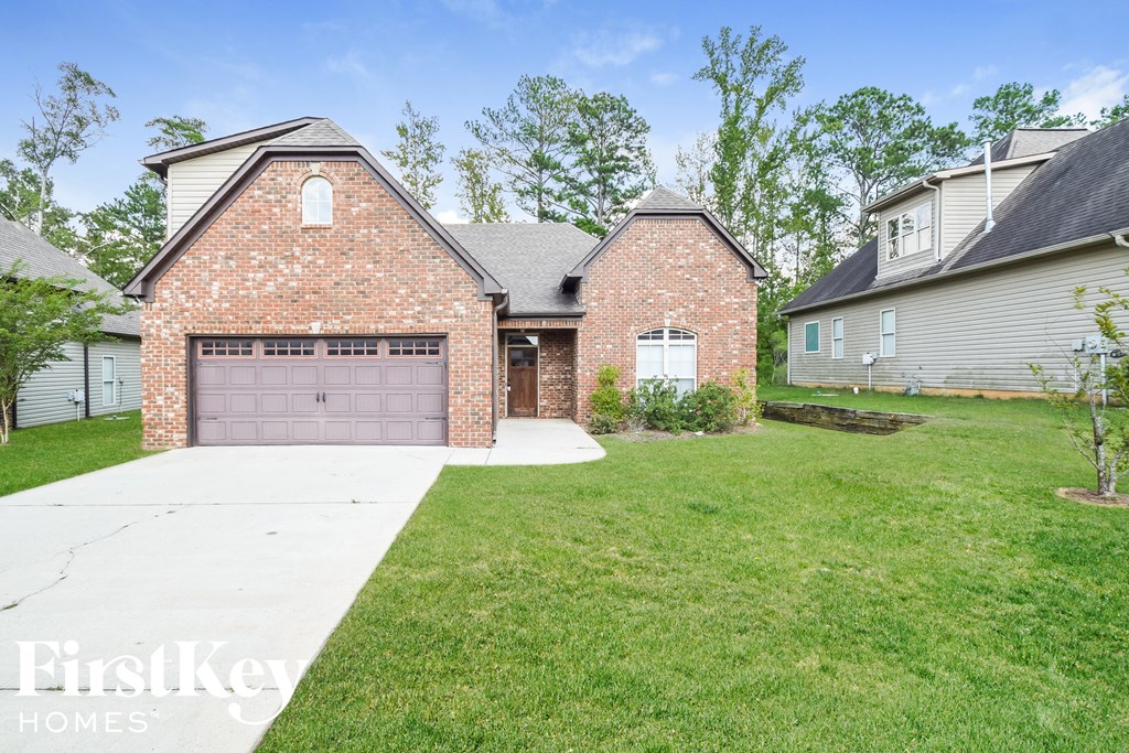 a brick home with a garage and a green lawn