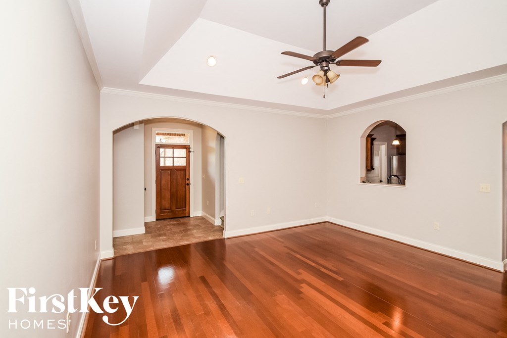 an empty living room with wood floors and a ceiling fan