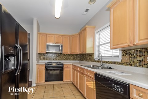 A kitchen with wooden cabinets and a black fridge.