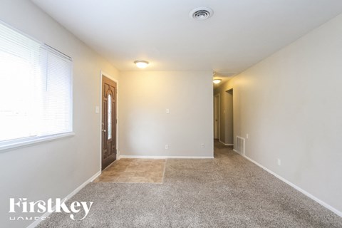 A spacious room with a carpeted floor and a door on the left.