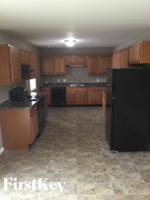 an empty kitchen with wooden cabinets and black appliances