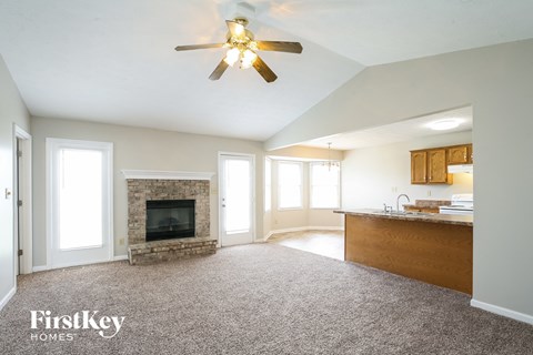 A spacious living room with a fireplace and a ceiling fan.