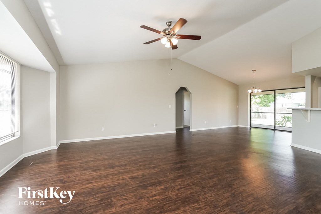 an empty living room with wood flooring and a ceiling fan