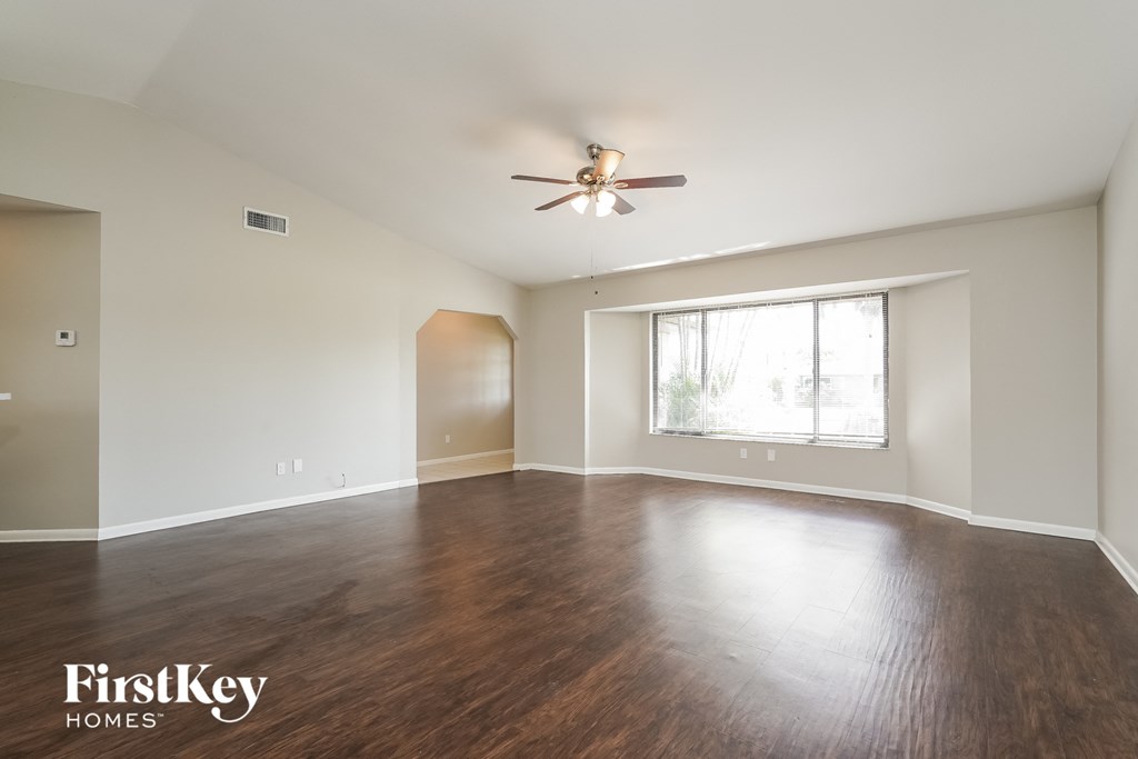 an empty living room with wood floors and a ceiling fan