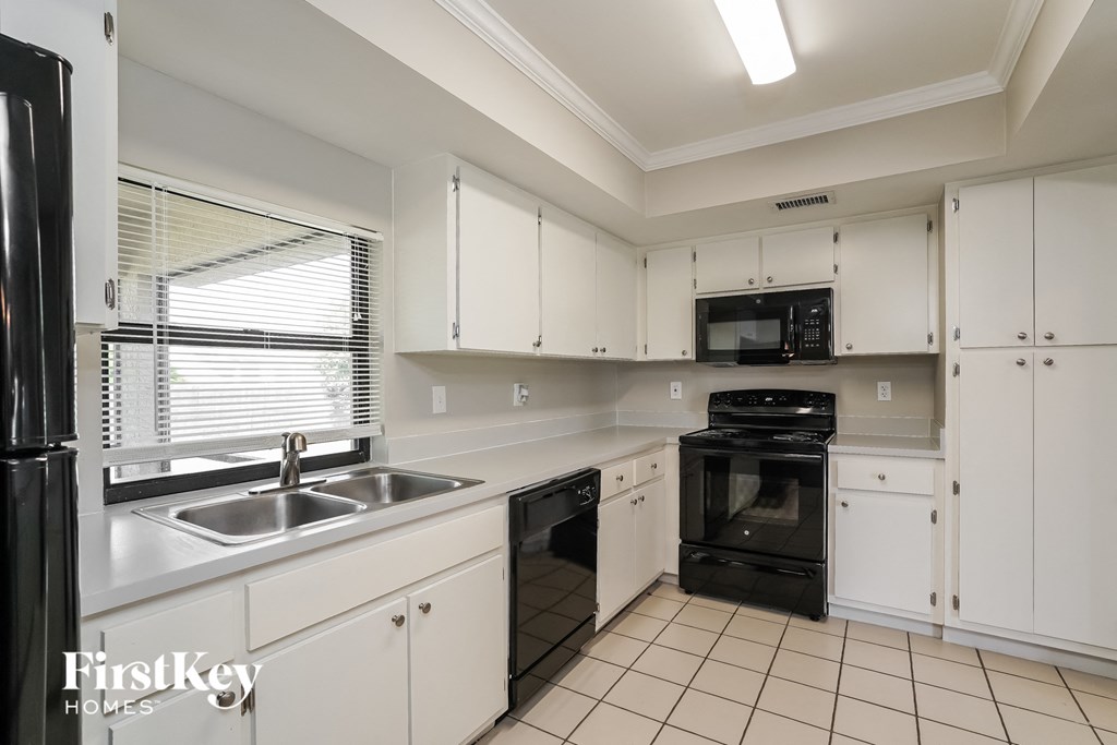 a kitchen with white cabinets and black appliances