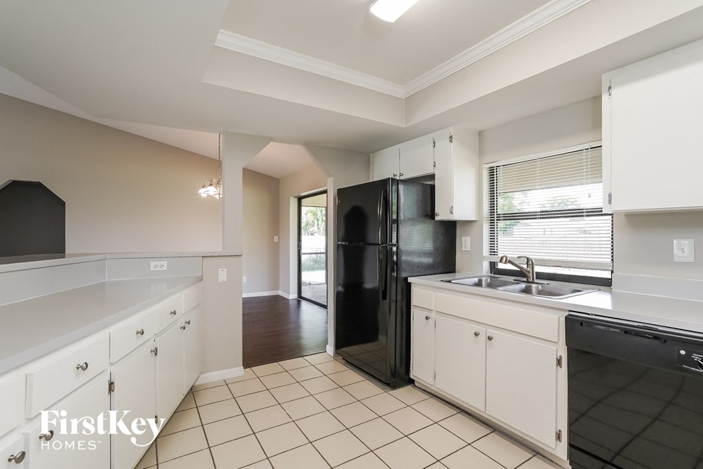 a kitchen with white cabinets and a black refrigerator and sink