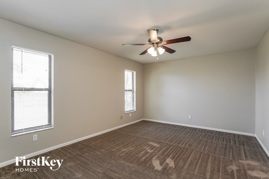 an empty living room with a ceiling fan and a window
