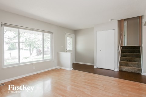 A room with wooden floors and a staircase leading to another room.