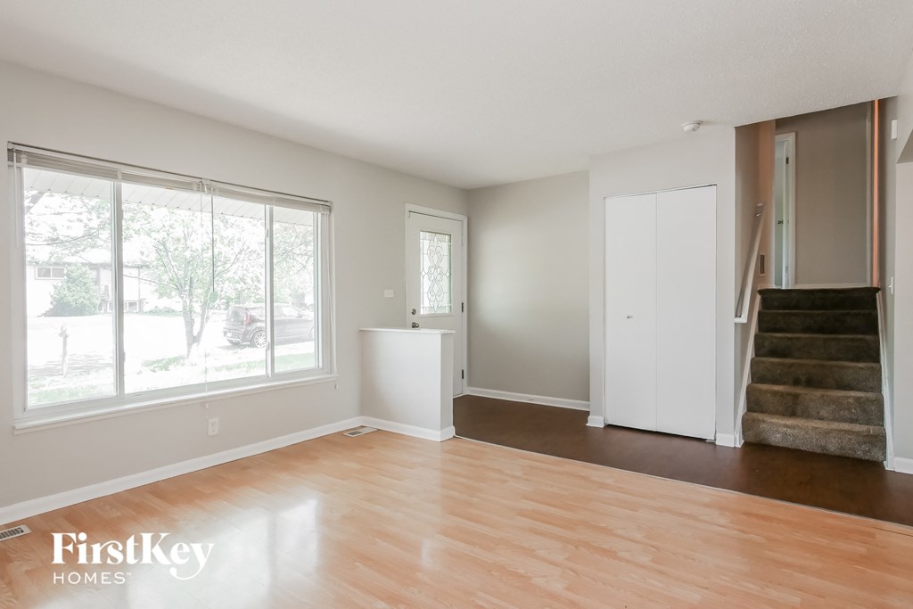 A room with wooden floors and a staircase leading to another room.