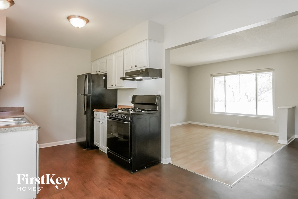 A kitchen with black appliances and wooden floors.