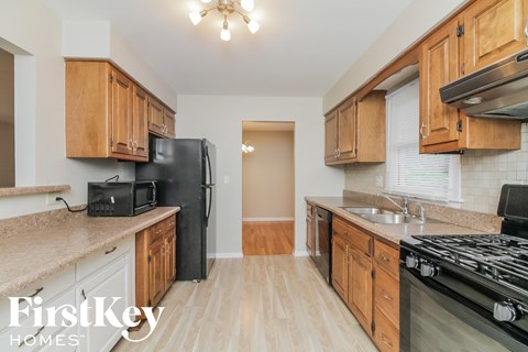 a kitchen with wood cabinets and black appliances and a stove top oven