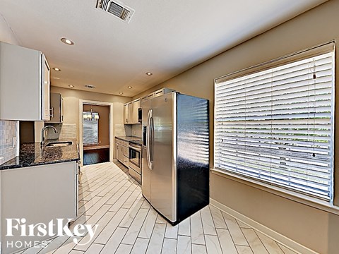A kitchen with a stainless steel refrigerator and a tiled floor.