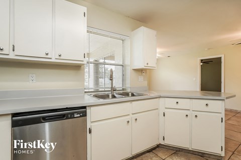 A kitchen with white cabinets and a FirstKey Homes logo.
