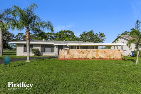 a house with palm trees in front of it and a grass yard