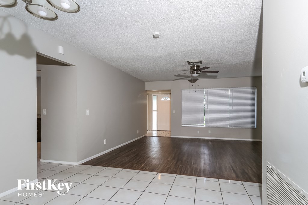 an empty living room with a ceiling fan and a window