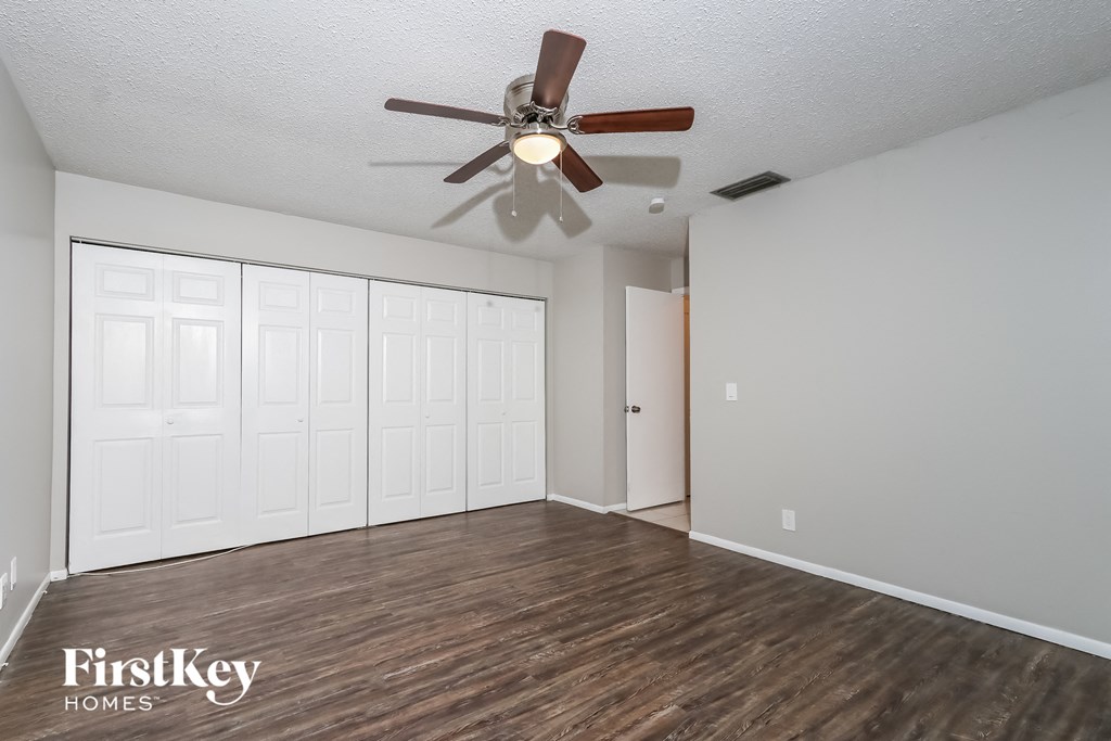 an empty living room with a ceiling fan and a closet