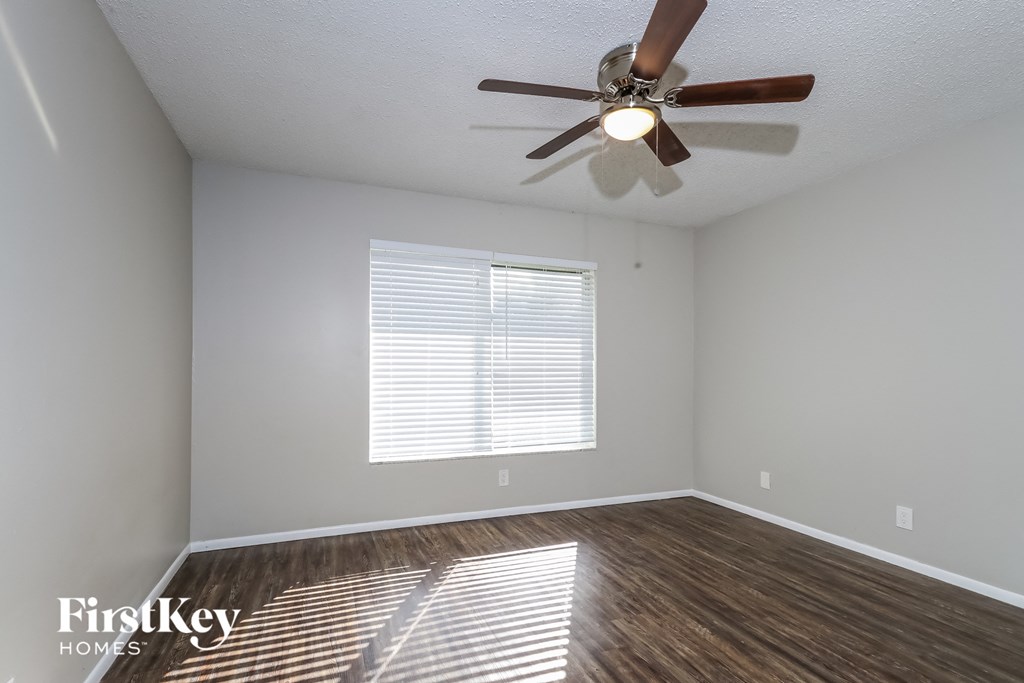 an empty room with a ceiling fan and a window