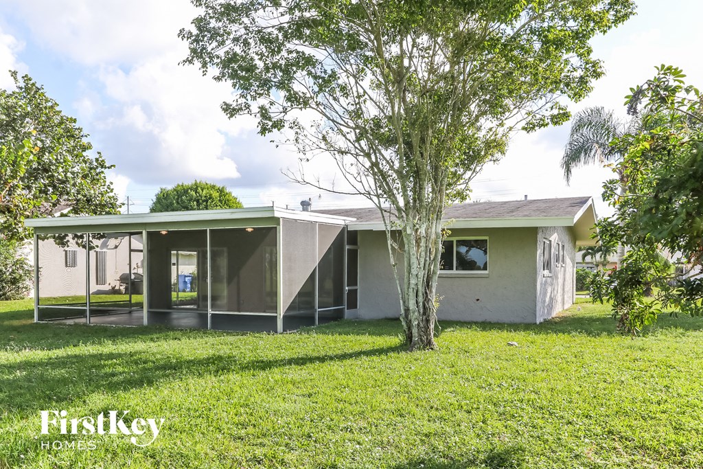 a small white house with a yard and a tree