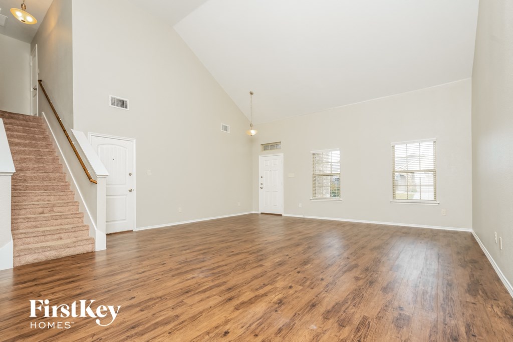 an empty living room with hardwood floors and a staircase