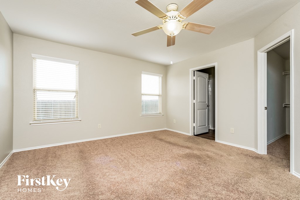 an empty living room with a ceiling fan and a door to a closet