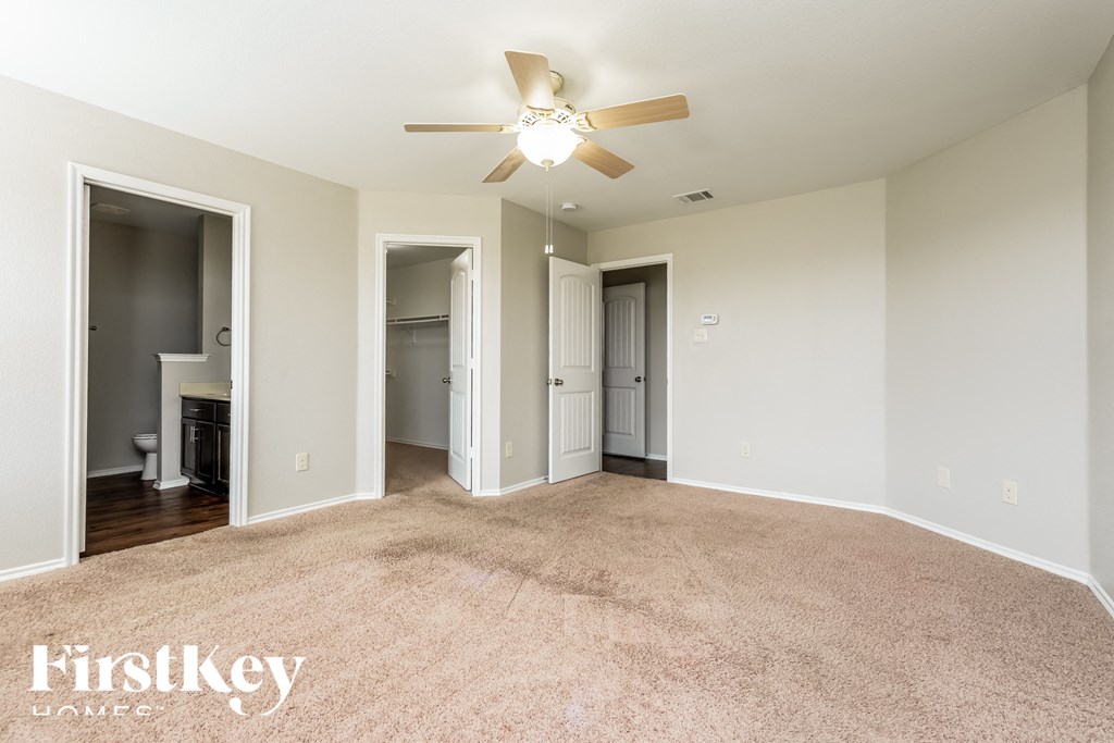 a spacious living room with carpet and a ceiling fan