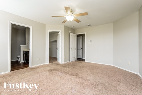 a spacious living room with carpet and a ceiling fan