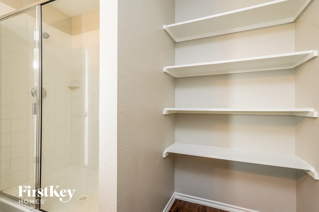 a walk in shower and white shelves in a bathroom