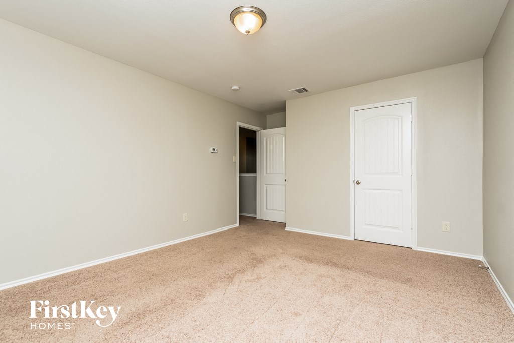 a spacious living room with carpet and a door to the kitchen