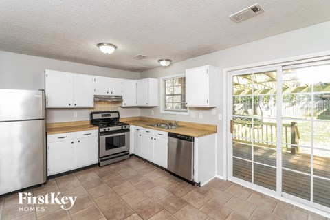 A kitchen with white cabinets and a refrigerator.